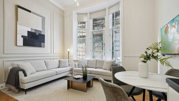 Una sala de estar moderna con sofá, mesa de centro y mesa de comedor.