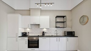 A modern kitchen with white cabinets, a built-in oven, a microwave, and a coffee maker. - (G5) Grand 1 bed Blythswood Apartment (Glasgow City)