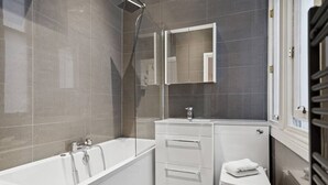 A modern bathroom with a bathtub, a toilet, and a vanity with a mirror. - (G5) Grand 1 bed Blythswood Apartment (Glasgow City)