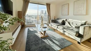 Ein modernes Wohnzimmer mit einer Couch, einem Couchtisch und einem großen Fenster mit Blick auf die Stadt.