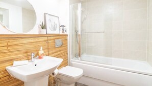 Een badkamer met een houten wastafel, een ronde spiegel, een toilet en een douchecabine.