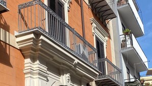 Een meerlaags gebouw met een klassieke architectuur, met een opvallende boogvormige ingang, balkons met metalen hekwerk en een gevel van baksteen en stucwerk.
