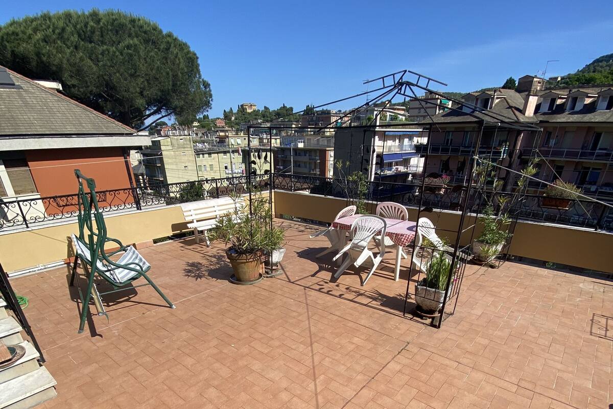 Eine Dachterrasse mit Backsteinpflaster, Gartenmöbeln, Kübelpflanzen und einem Metallgeländer.
