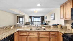 A kitchen with granite countertops, wooden cabinets, a stainless steel sink, and a dishwasher.