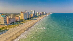A coastal cityscape with high-rise buildings along a beach.