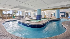 An indoor swimming pool with a 3 FT depth marker, surrounded by a brick deck and a covered seating area with tables and chairs.