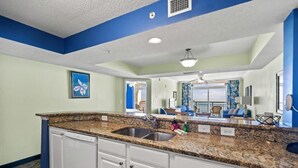 A kitchen with granite countertops, white cabinets, and a double sink.