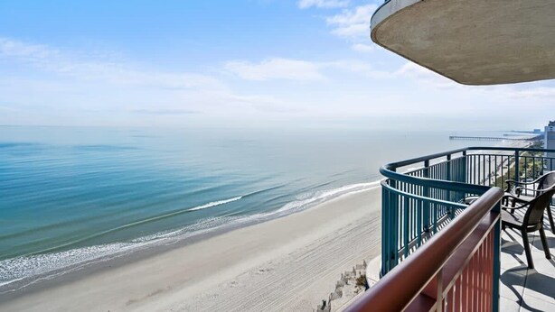 A balcony with a view of a beach and ocean.