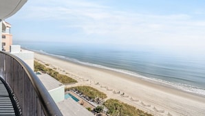 A beach view from a balcony with a pool and lounge chairs. - Compass Cove Resort Unit 1216 - Oceanfront (Myrtle Beach)