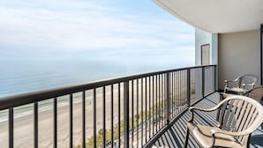 A balcony with a view of the beach and ocean. There are two wicker chairs and a small table. - Compass Cove Resort Unit 1216 - Oceanfront (Myrtle Beach)