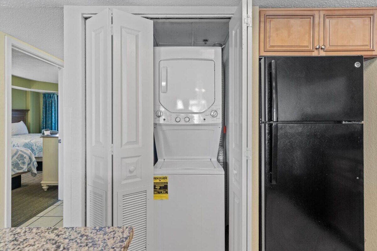 Eine kleine Küchenzeile mit Waschmaschine, Kühlschrank und Holzausstattung.