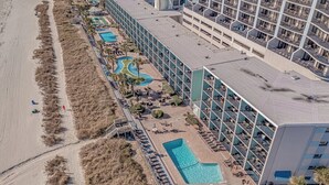 Vue aérienne d’un hôtel doté de plusieurs piscines, d’une plage et d’un grand bâtiment avec des balcons.
