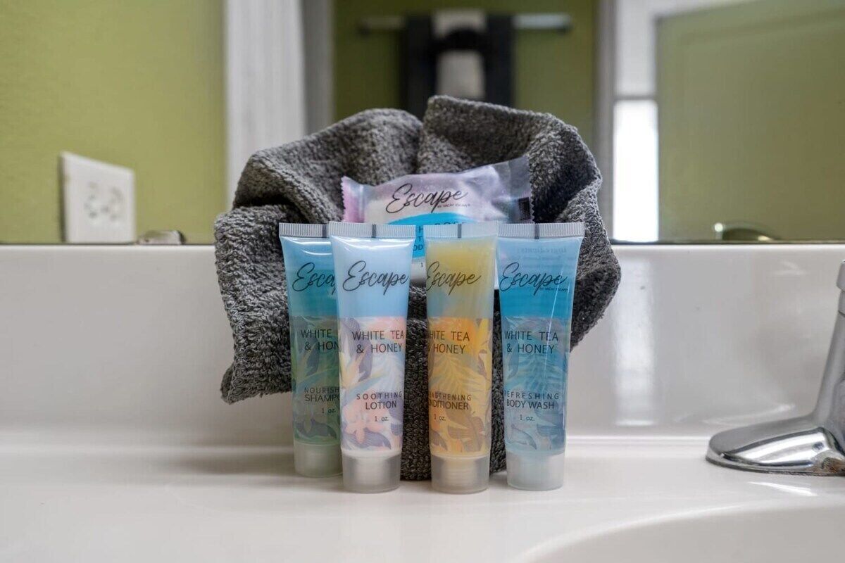 A bathroom sink with four bottles of Escape brand toiletries.