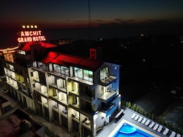 Un hotel de varios pisos con piscina en la azotea y un letrero llamativo.