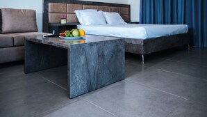 Une chambre d’hôtel moderne équipée d’un lit, d’un canapé, d’une table basse en marbre et d’un panier de fruits.