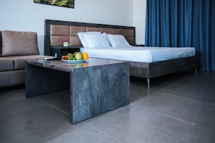 Una habitación de hotel moderna con una cama, un sofá, una mesita de centro de mármol y un frutero.