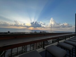 Un balcón con vista al mar y una torre alta en la distancia.