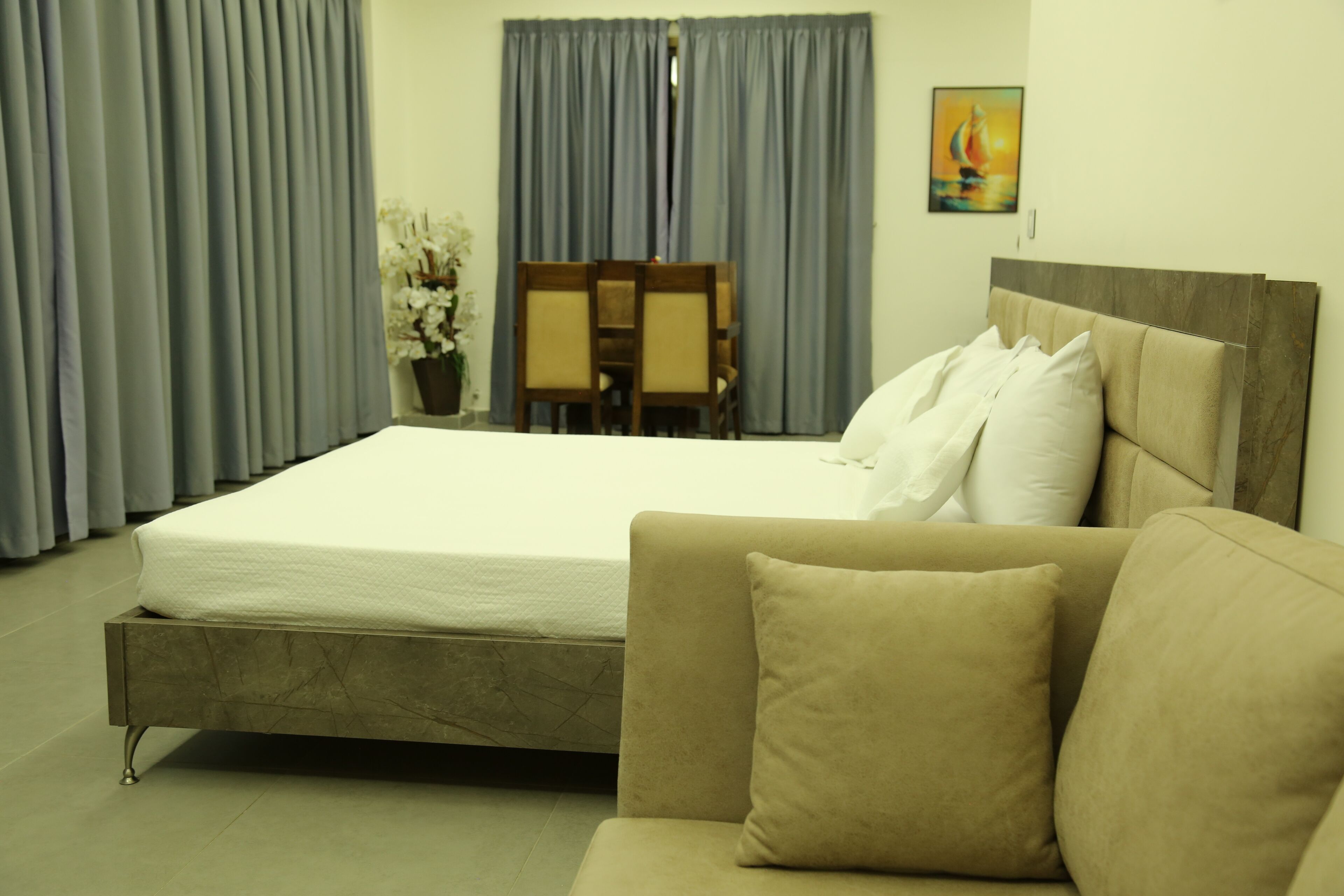 Un dormitorio con cama, sofá, mesa de comedor con sillas y un cuadro en la pared.
