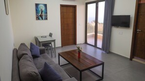 Un salon avec un canapé, une table basse, un téléviseur et un balcon offrant une vue agréable.