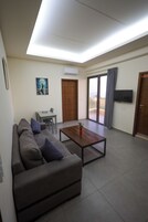 Una sala de estar con sofá, mesa de centro, televisor y balcón con vistas.