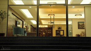 Un hall d’hôtel avec un grand escalier, un fauteuil bleu et des lustres.