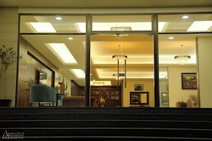 Un vestíbulo de hotel con una imponente escalera, un sillón azul y candelabros.