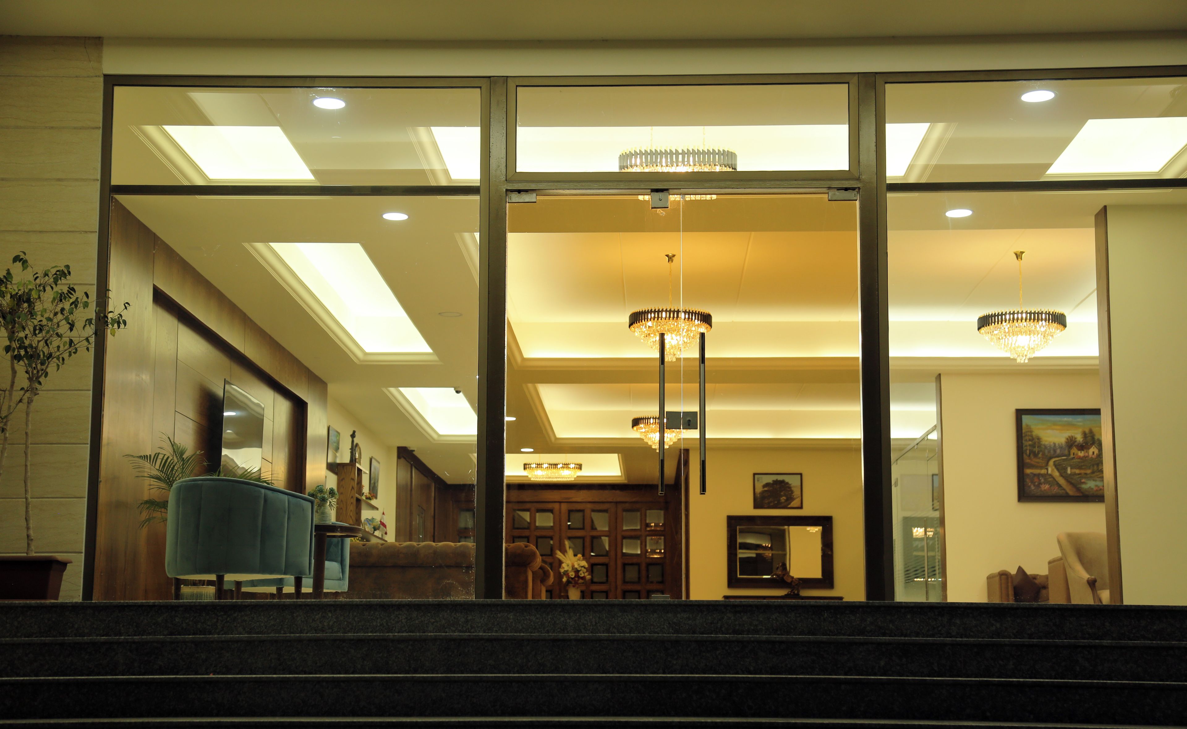 Eine Hotellobby mit einer imposanten Treppe, einem blauen Sessel und Kronleuchtern.
