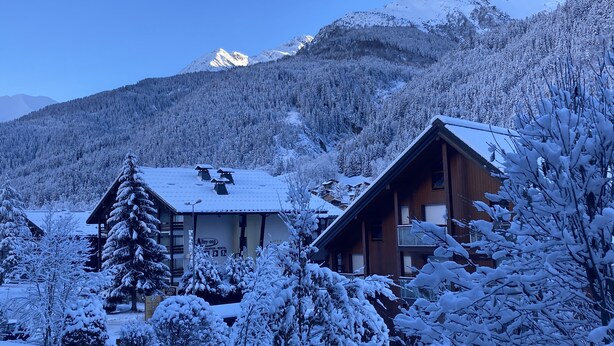 A wooden cabin with a snow-covered roof, surrounded by snow-laden trees and mountains in the background. - 1 bedroom apartment 27 m2 4 People near the Gondola (Les Contamines-Montjoie)