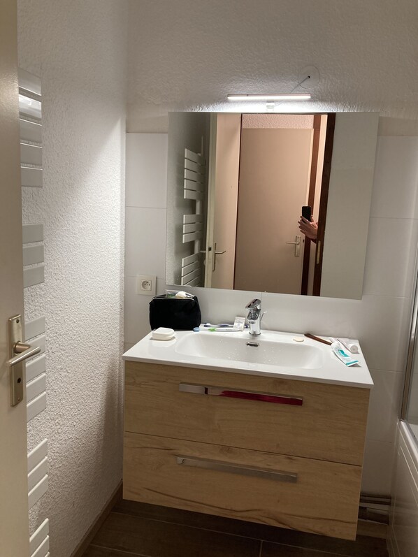 Une salle de bain avec un lavabo blanc, un miroir et un meuble en bois.