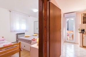 Un dormitorio con cama, mesita de noche y ventana con cortinas.