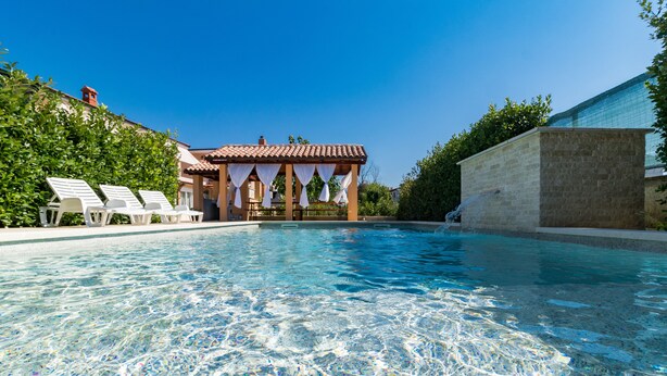 A clear swimming pool with lounge chairs and a covered seating area. - Apartments Kendel (Fazana)