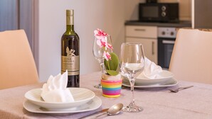 A dining table set with plates, a wine bottle, a glass, and a small vase with flowers. - Apartments Kendel (Fazana)