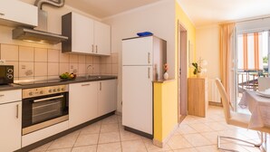 A modern kitchen with white cabinets, a stainless steel oven, and a built-in microwave. - Apartments Kendel (Fazana)