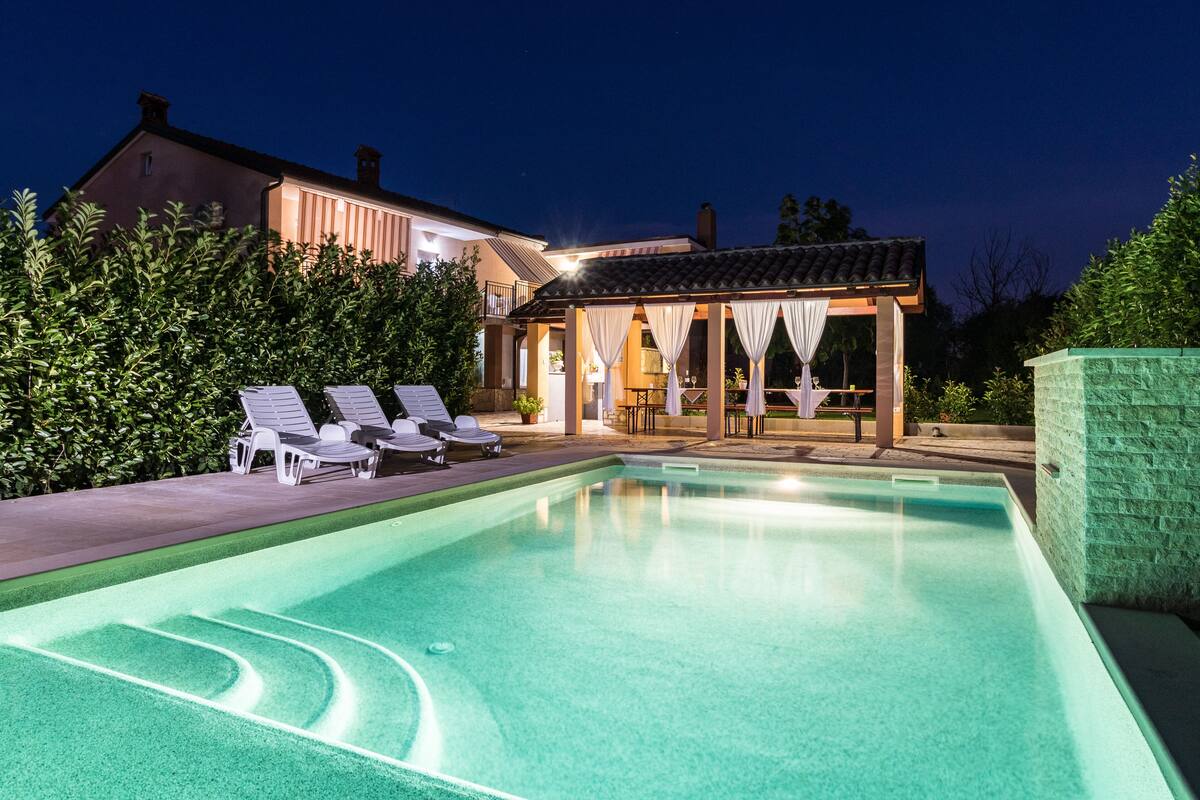 Ein Pool mit Liegestühlen und einer überdachten Terrassenbereiches.
