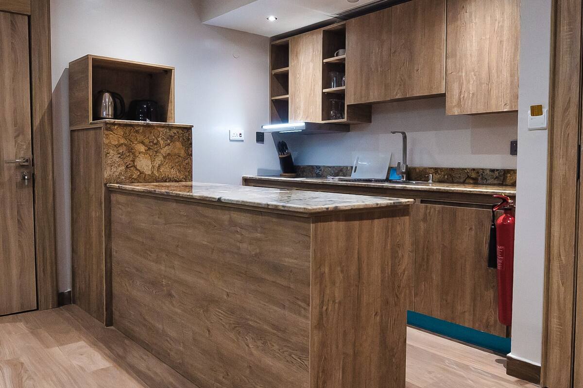 A modern kitchen with wooden cabinetry, a marble countertop, and a built-in stove.