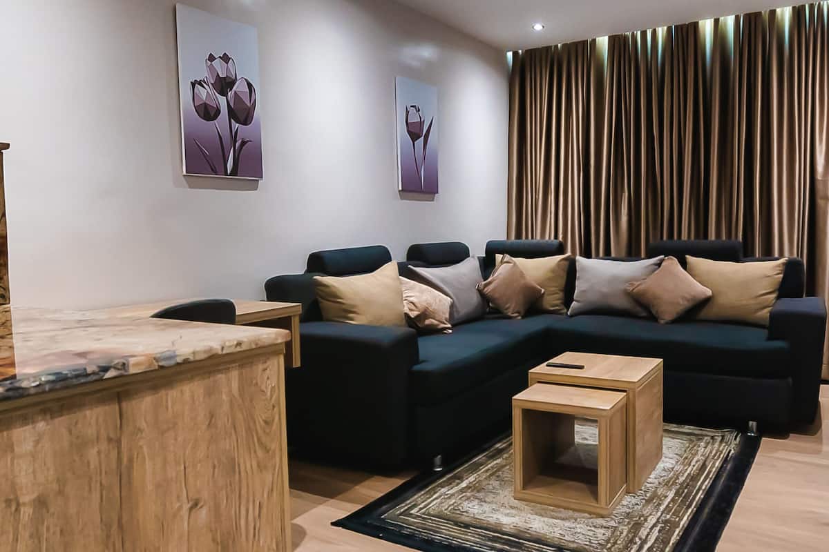 A modern living room with a sectional sofa, a wooden coffee table, and a flat-screen TV mounted on the wall.