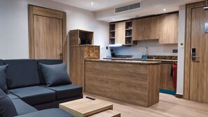 A modern living room with a sofa, a coffee table, and a kitchen area with wooden cabinets and a countertop. - Sunflower Residence Victoria Island (Lagos)