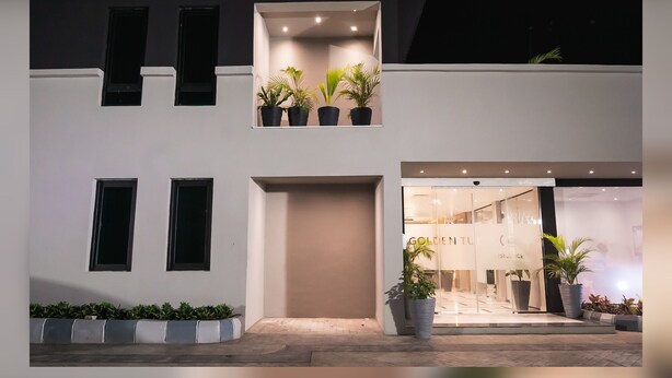 A modern building with a flat facade, multiple windows, and a central entrance. There are potted plants on the ground level and on the balcony. - Sunflower Residence Victoria Island (Lagos)