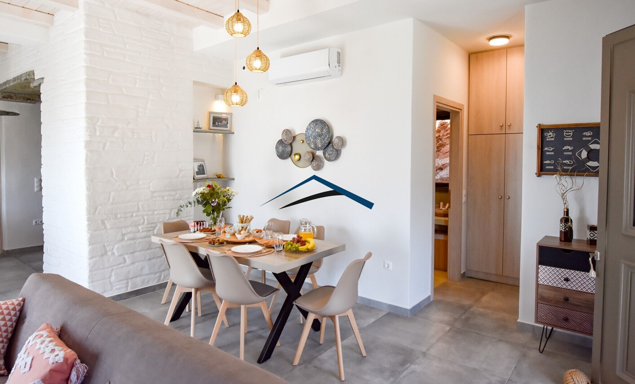 A modern dining area with a white brick wall, a wooden dining table set with chairs, and decorative wall art.