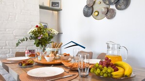A breakfast setting with a wooden table, plates, a pitcher of orange juice, a bowl of fruit, and a vase with flowers. - Mavrabeli Sunset Retreat, with amazing sea and sunset view, 15 minutes from port (Kéa)