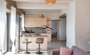 A modern kitchen with a central island, two bar stools, and a hanging light fixture. - Mavrabeli Sunset Retreat, with amazing sea and sunset view, 15 minutes from port (Kéa)