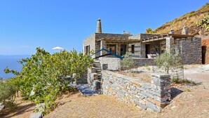 A stone building with a chimney, a patio, and a view of the sea. - Mavrabeli Sunset Retreat, with amazing sea and sunset view, 15 minutes from port (Kéa)