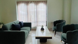 A living room with a sofa, two armchairs, a coffee table, and a window with curtains. - Tshongdu Boutique (Paro)