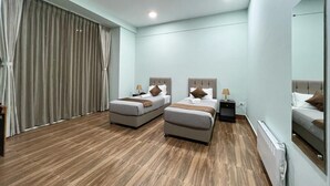 A hotel room with two beds, a ceiling fan, a large window with curtains, and a mirror on the wall. - Tshongdu Boutique (Paro)