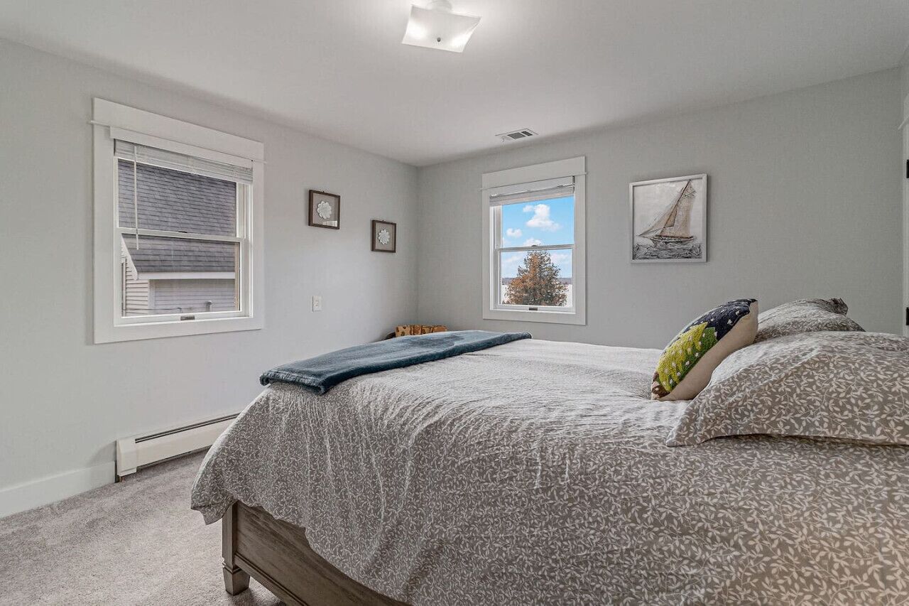 A bedroom with a bed, two windows, and a ceiling light.