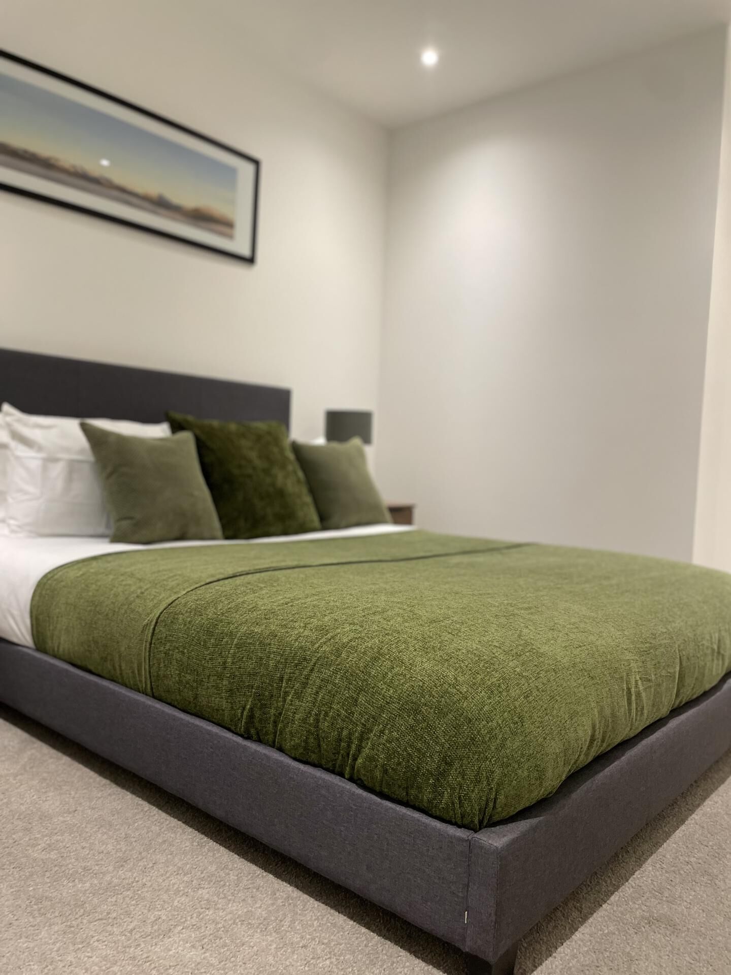 A modern bedroom with a bed, pillows, and a nightstand.