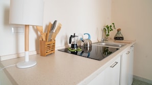 A kitchen with a coffee maker, kettle, and utensils on the counter.
