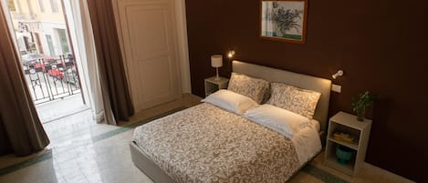 Une chambre à coucher avec un lit, des tables de chevet, une lampe fixée au mur et une plante en pot.