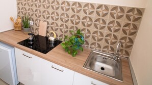 Cocina con estufa negra, pileta de acero inoxidable y un salpicadero con diseño.