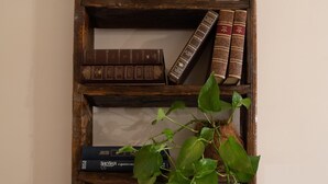 Una estantería de madera con libros y una planta en maceta.